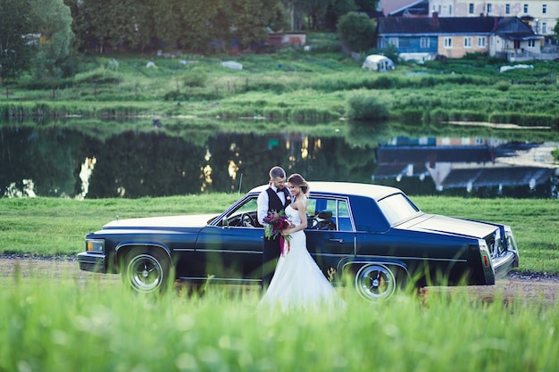 Hochzeitspaar steht in der Nähe des Retro-Oldtimers