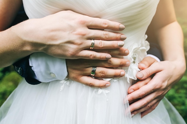 Foto hochzeitspaar umarmt sich im freien braut und bräutigam halten sich an den händen liebeskonzept elegante kleidung