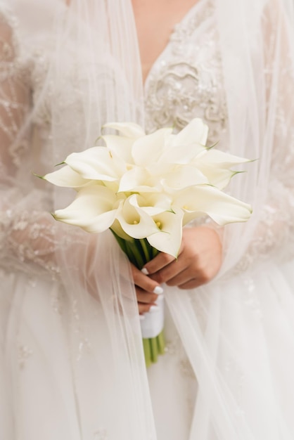 Hochzeitsstrauß aus weißen Calla-Lilien in die Hände der Braut