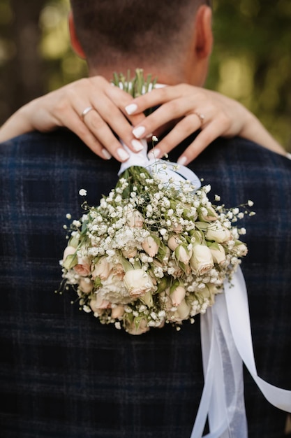 Hochzeitsstrauß aus weißen Rosen in den Händen der Braut