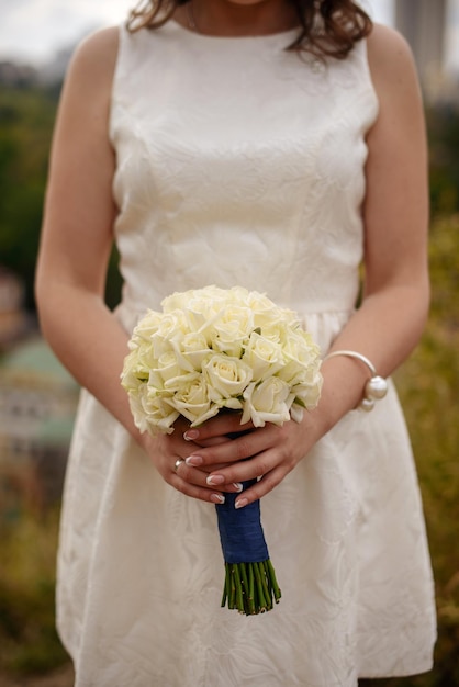 Hochzeitsstrauß aus weißen Rosen in den Händen der Braut