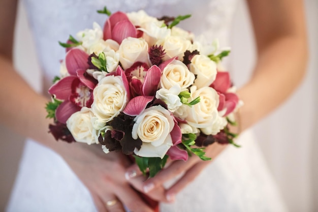 Hochzeitsstrauß aus weißen und rosafarbenen Pfingstrosen und Rosen in Brauthänden