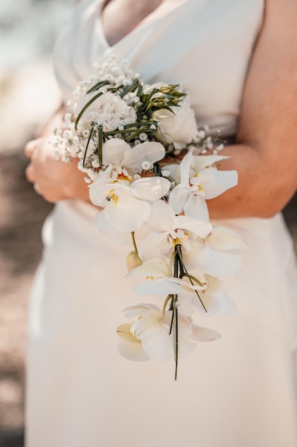 Hochzeitsstrauß in den Händen der Braut Die Braut in einem beigen Kleid hält die Blumen Hochzeitsstrauß aus Blumen und Grün