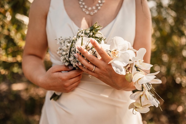 Hochzeitsstrauß in den Händen der Braut Die Braut in einem beigen Kleid hält die Blumen Hochzeitsstrauß aus Blumen und Grün
