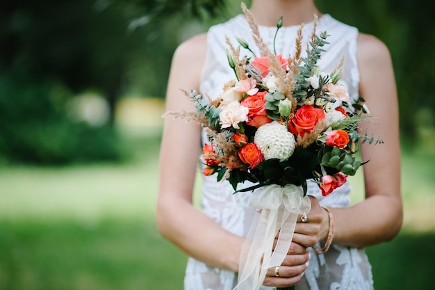 Hochzeitsstrauß in den Händen der Braut mit roten Blumenrosen