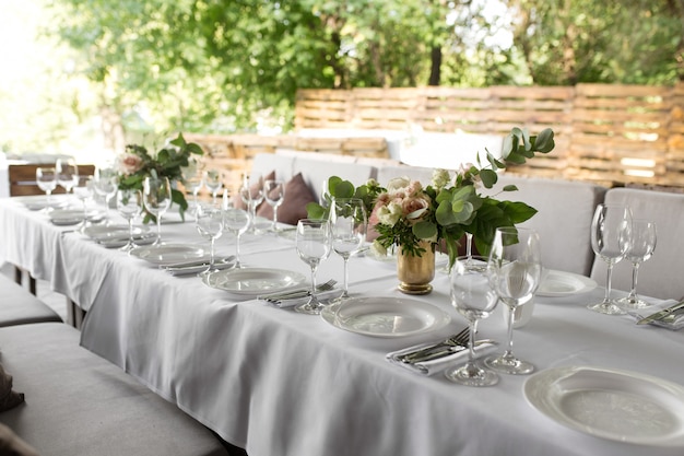 Hochzeitstafeleinstellung verziert mit frischen Blumen in einem Messingvase