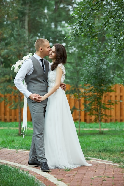 Hochzeitstag, ein verliebtes Paar, das sich im Park umarmt und küsst. Mann umarmt schöne Frau, Verlobung