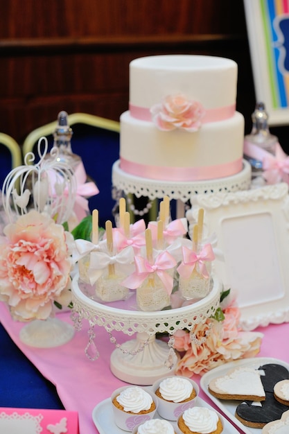 Hochzeitstorte dekoriert mit roten Rosen und Cupcakes