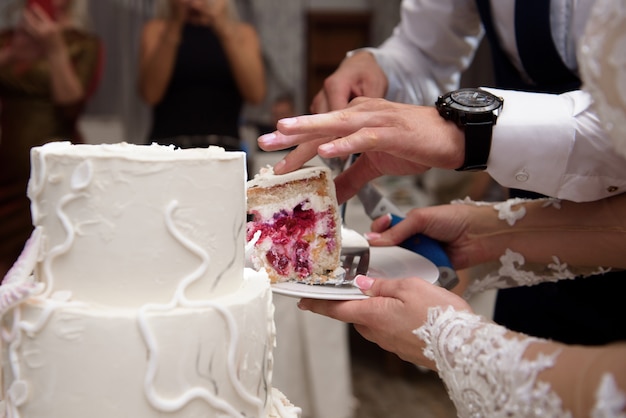 Hochzeitstorte. Eine Braut und ein Bräutigam schneiden ihre Hochzeitstorte