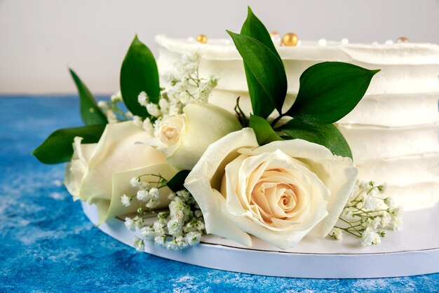 Hochzeitstorte mit weißen rosen auf blauem hintergrund. nahansicht.