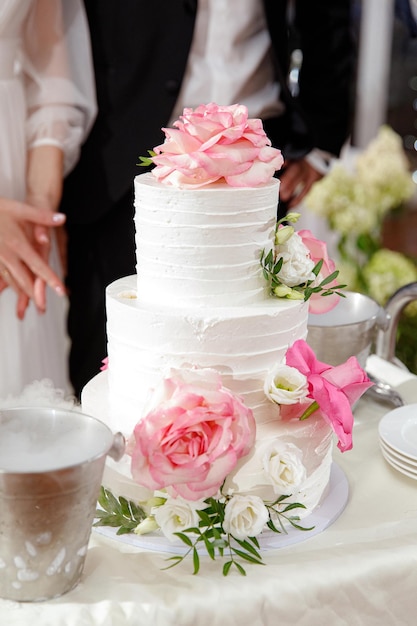 Foto hochzeitstorte mit weißer sahneglasur wird die süße blumendekoration auf dem tisch aufhellen