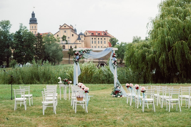 Hochzeitszeremonie auf der Straße auf dem grünen Rasen. Dekor mit frischen Blumenbögen für die Zeremonie.