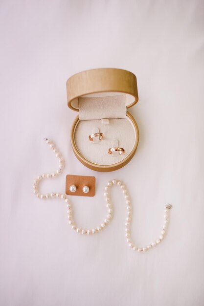 Hochzeitszubehör für die Braut Ringe, Ohrringe und Halskette auf weißem Hintergrund
