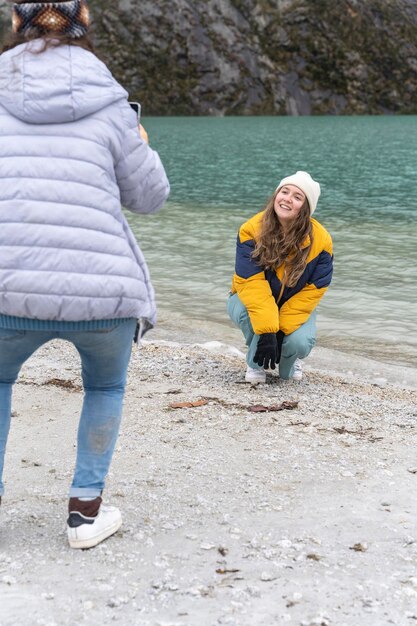 Hockendes Mädchen, während ein Freund ein Foto von ihr mit dem Telefon in einer Lagune macht