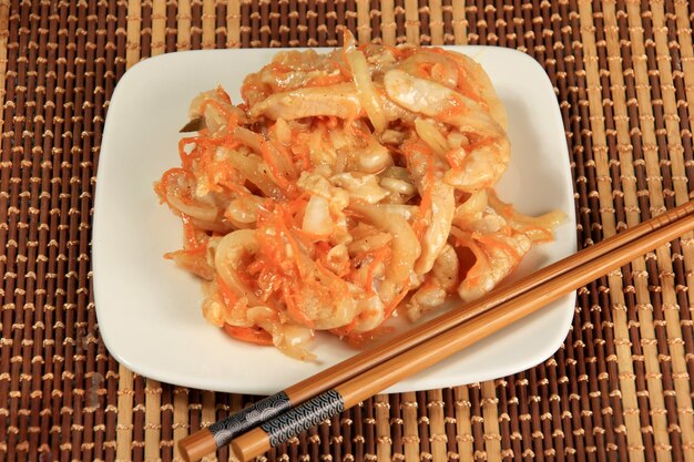 Hoe - Geschnittener roher Fisch mit Zwiebeln und Karotten auf Bambushintergrund