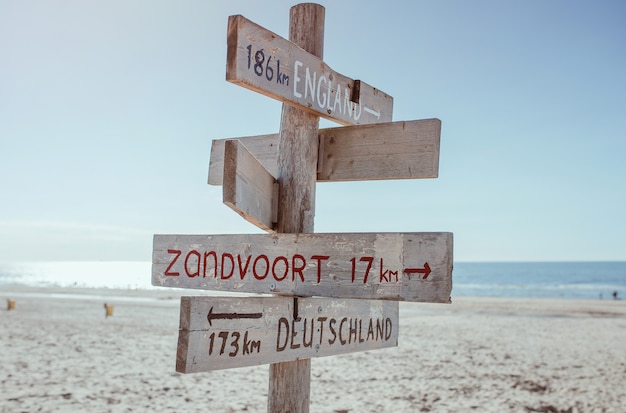 Hölzerne Informationstafel mit Entfernung nach England Deutschland und Zandvoort am Strand Nordsee north