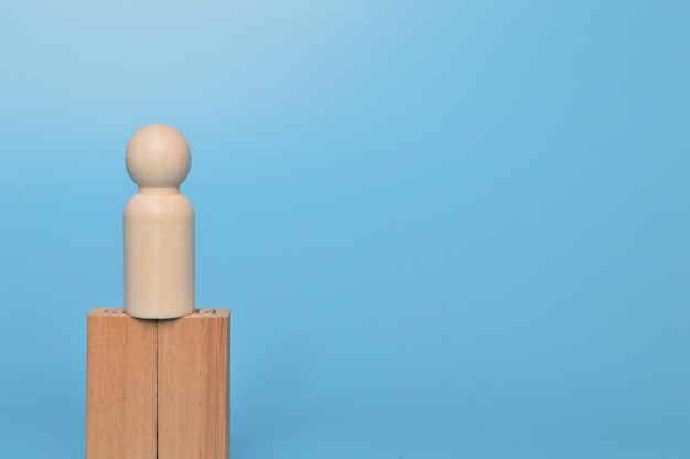 Hölzerne Puppenfiguren, die auf einem Holzblock stehen. Unternehmensführungskonzept