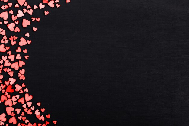 Hölzerne rote Herzen auf einer schwarzen Tabelle