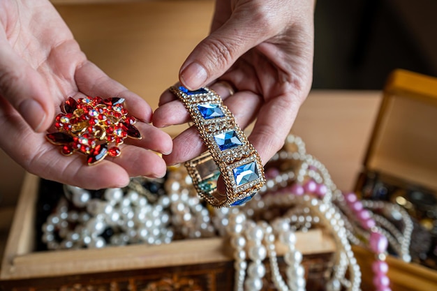 Hölzerne Schatzkiste mit Wertsachen Eine Frau hält Perlenketten und anderen Schmuck in ihren Händen