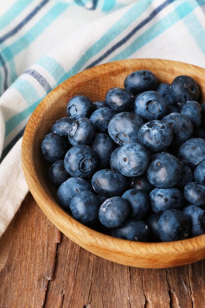 Hölzerne Schüssel Blaubeeren auf Serviette auf hölzerner Hintergrundnahaufnahme Beschneidungspfad eingeschlossen