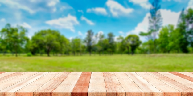 Hölzerne Tischplatte mit grüner Parknatur verwischte Hintergrund