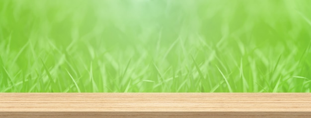 Hölzerne Tischplatte und grünes Gras der Unschärfe für Produkt- und Anzeigenmontagefahnengröße.