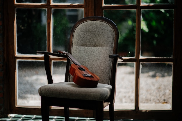 Hölzerne Ukulele Browns, die auf einem Holzstuhl stillsteht