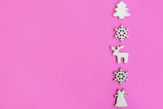 Hölzerne Weihnachtsspielzeuge auf rosa Hintergrund, Draufsicht, flache Lage, minimales Neujahrskonzept, für Design oder Postkarte