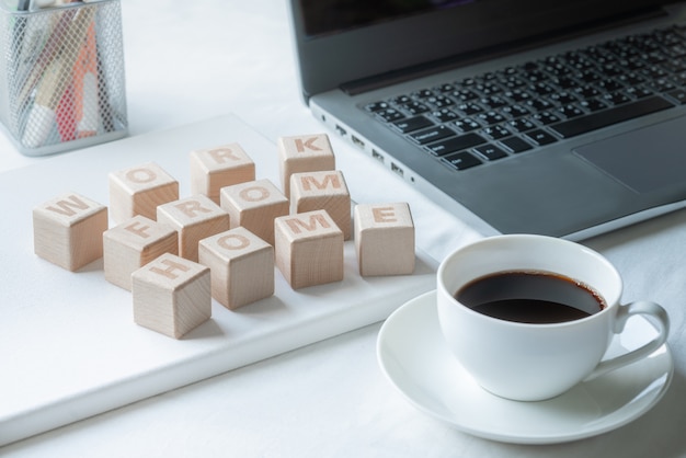 Hölzerne Wortblöcke Arbeiten Sie von zu Hause aus auf dem Schreibtisch mit Laptop und Kaffeetasse