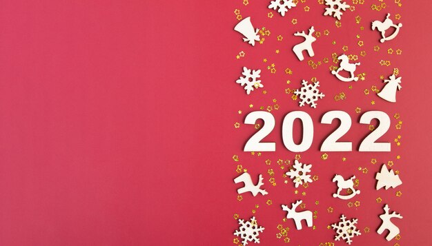 Hölzerne Zahlen für neues Jahr mit Sternen und Weihnachtsdekor auf rotem Hintergrund mit Kopienraumfahne...