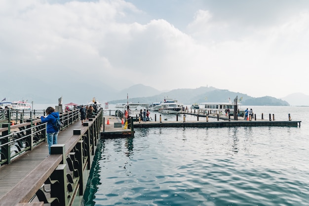 Hölzerner Gehweg, der zum Boot in Sun Moon Lake mit Berg und Wolke führt