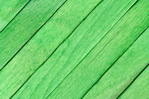 Hölzerner gemalter Hintergrund. Grüne Bretter aus Holz sind diagonal angeordnet. Strukturierter bemalter Karton