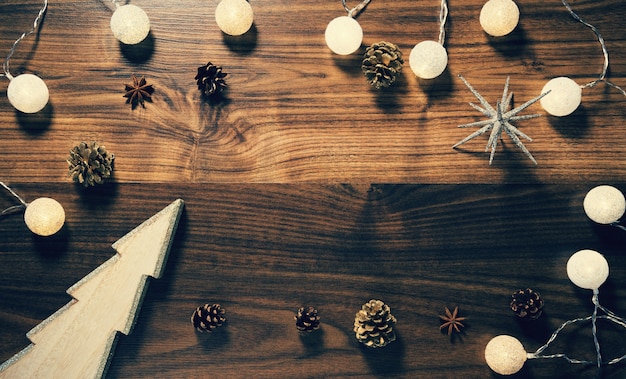 Foto hölzerner hintergrund mit dekorativem weihnachtsbaum, girlande und tannenzapfen.