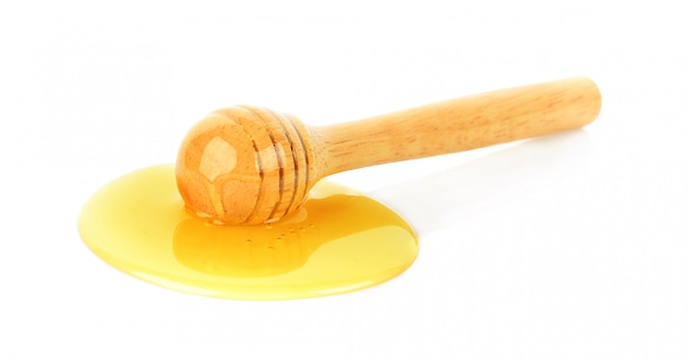 Hölzerner Honigschöpflöffel mit Honig auf weißem Hintergrund