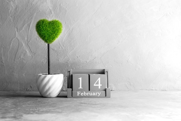 Hölzerner Kalender der Weinlese für den 14. Februar mit grünem Herzen auf hölzerner Tabelle