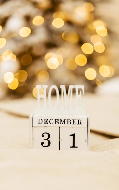 Hölzerner Kalender von Blöcken mit dem Datum vom 31. Dezember auf dem verschwommenen Hintergrund von Weihnachten und Neujahr. Schönes warmes helles Bokeh. Neujahrsstimmung. Foto