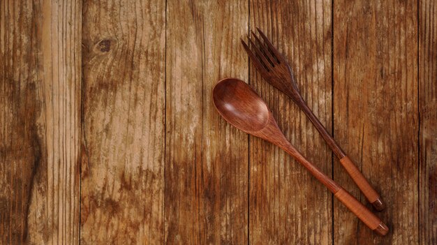 Hölzerner Löffel und Gabel auf hölzernem Hintergrund. Holzgeräte im asiatischen Stil. Platz kopieren