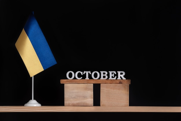 Hölzerner Oktoberkalender mit ukrainischer Flagge auf schwarzem Hintergrund. Termine in der Ukraine im Oktober.