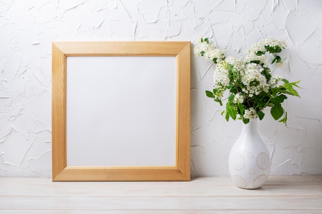 Hölzerner quadratischer Bilderrahmen mit zarten Viburnum-Blumen in der dekorierten Vase. Leerer Rahmen für Präsentationsdesign. Vorlagenrahmen für moderne Kunst.