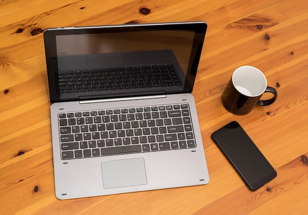 Hölzerner Schreibtischtisch mit Laptop, Cup und Smartphone. Draufsicht.