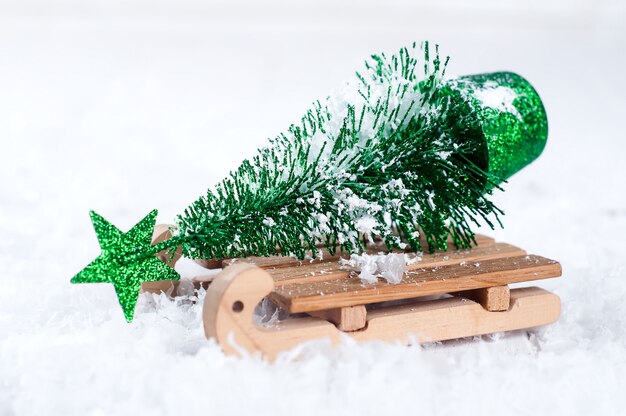 Hölzerner Winterpferdeschlitten, der einen kleinen Weihnachtsbaum trägt