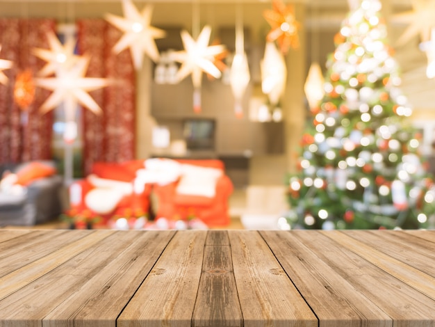 Hölzernes Brett leere Tischplatte auf unscharfen Hintergrund. Perspektive braun Holz Tisch über Unschärfe Weihnachtsbaum und Kamin Hintergrund, kann verwendet werden Mock up für Montage Produkte Display oder Design-Layout