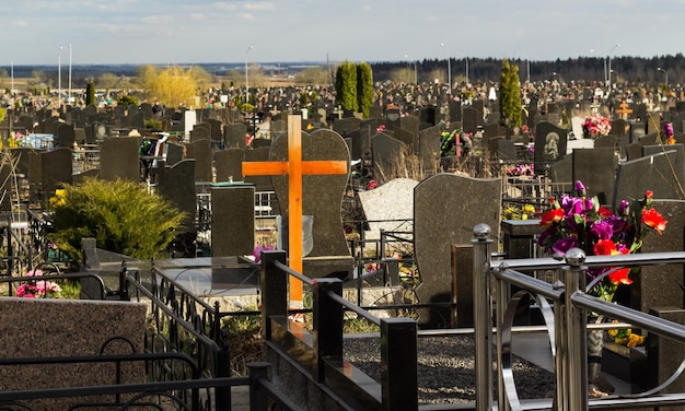 Hölzernes Grabkreuz mit künstlichen Blumen bei Sonnenuntergang Orthodoxer traditioneller Friedhof