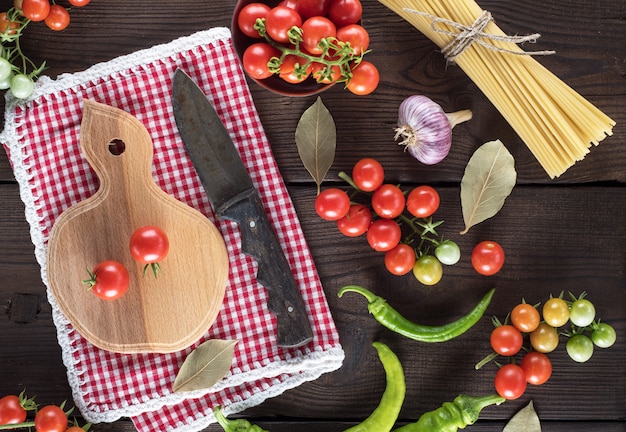 Hölzernes Schneidebrett mit einem Messer und frischen roten Kirschtomaten