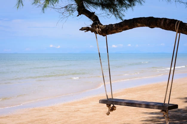 Hölzernes Schwingen, das von einem Baum auf dem Strand, im südlichen Teil von Thailand am sonnigen Tag hängt.