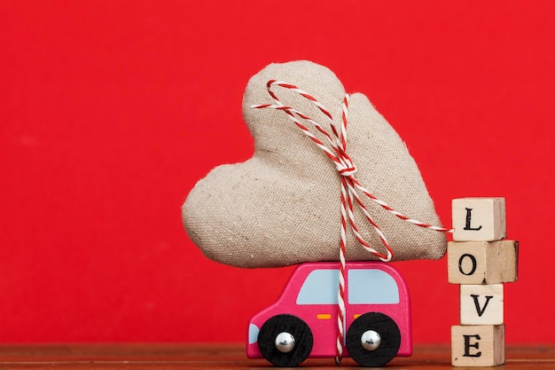 Hölzernes Spielzeugauto mit einem Liebesherz Valentinstag-Muttertagskonzept