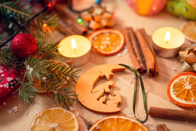 Hölzernes Weihnachtsbaumspielzeug mit biblischer Illustration, die auf dem Tisch unter heller festlicher Dekoration liegt