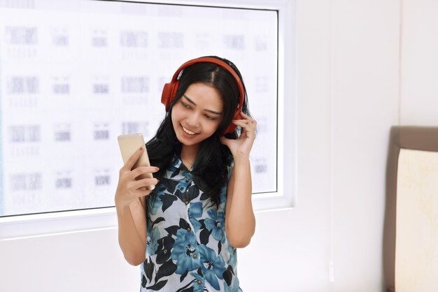 Hörende Musik der glücklichen asiatischen Frau mit Kopfhörer