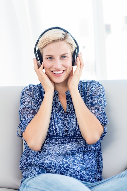 Hörende Musik der hübschen Blondine auf der Couch