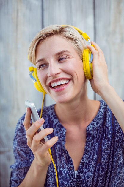 Hörende Musik der hübschen Blondine mit ihrem Handy